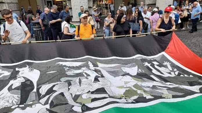 Striscione con la bandiera della Palestina ed una riproduzione di Guernica di Pablo Picasso